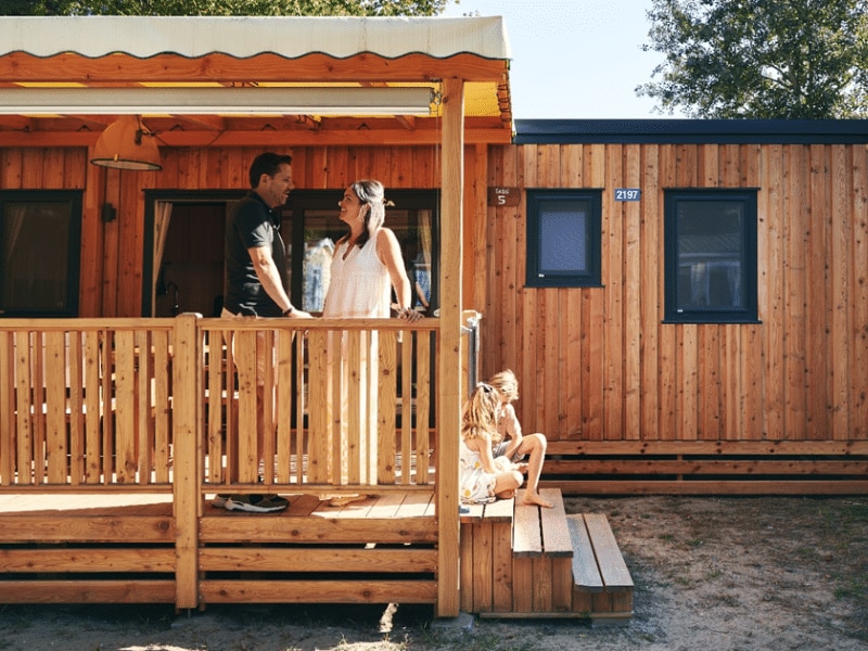 SunLodge Sabai mit Paar mit zwei Kindern, die auf der Treppe zur Verande der SunLodge sitzen