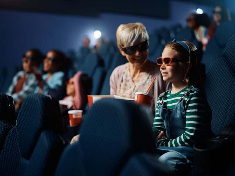 Mutter mit Tochter mit 3D-Brillen im Kino, mit Popcorn