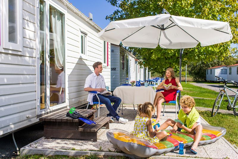 Zu einem Mobilheim gehört oft auch eine Terrasse für gemeinsame Stunden mit der Familie.