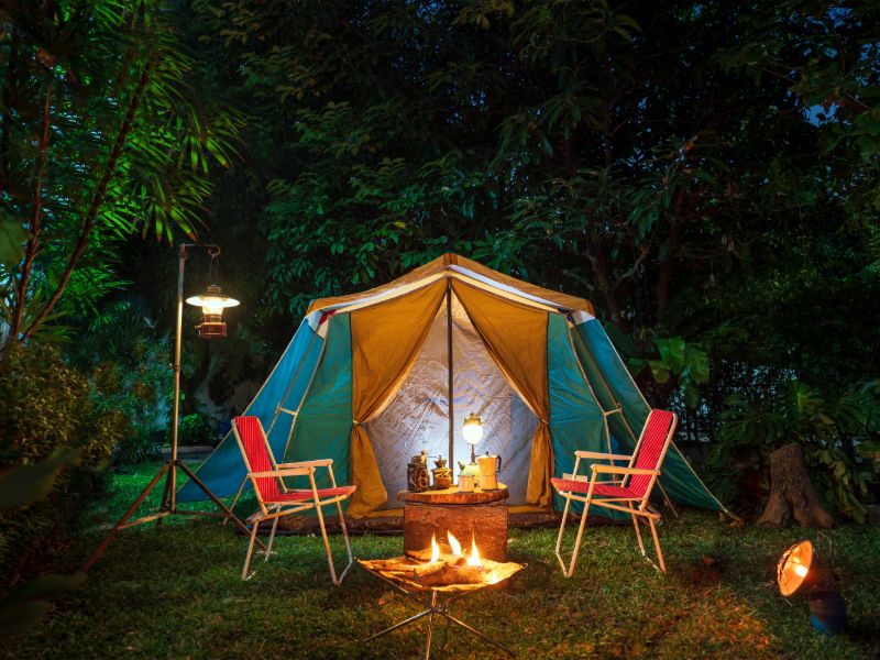 Zwei Campingstühle vor einem Zelt mit Lagerfeuer