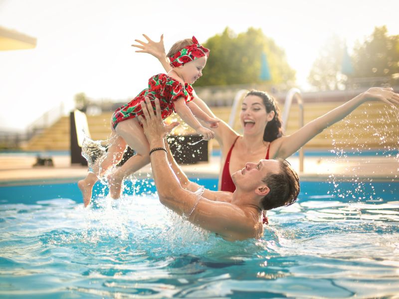 Frau und Mann mit kleinem Mädchen im Pool